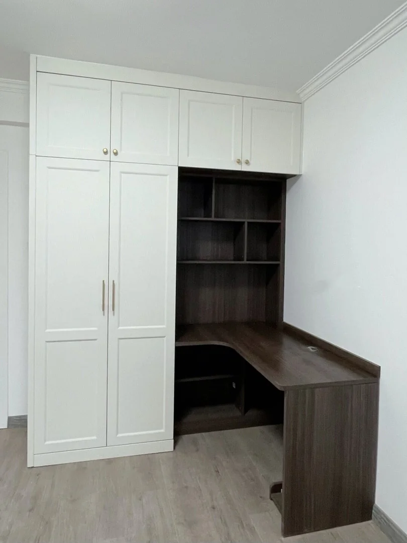 White classic panel wardrobes joined to a dark L-shaped desk and open shelves in a Singapore bedroom