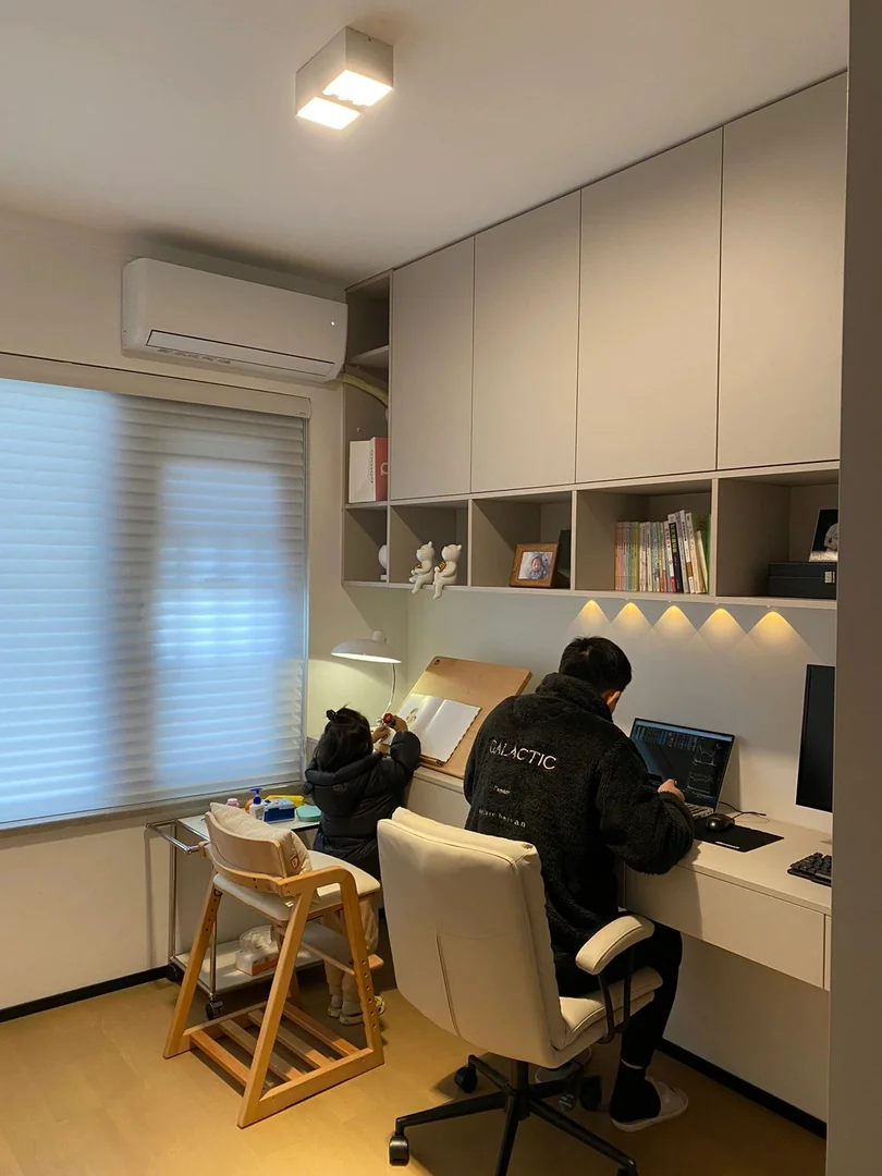 Parent and child using a custom family study table with overhead cabinets in a Singapore home