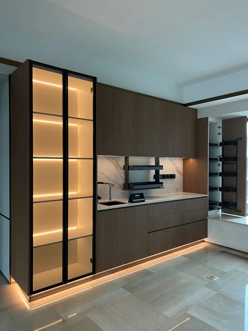 Dark wood kitchen dry pantry with illuminated glass display cabinet and compact coffee counter in a Singapore home